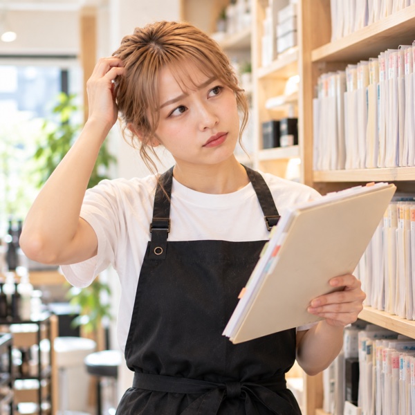 棚の紙のカルテを探して困っているアシスタント