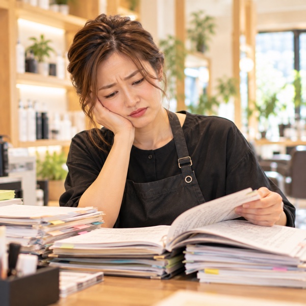 何冊ものカルテをめくって過去の記録を探すスタイリスト